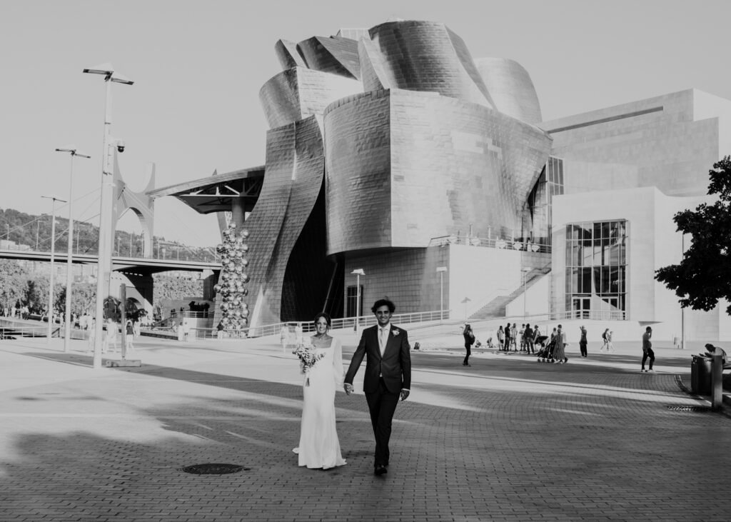 Retrato de pareja con reflejos sobre la ría de Bilbao frente al Museo Guggenheim, fotografía de boda moderna y artística.
